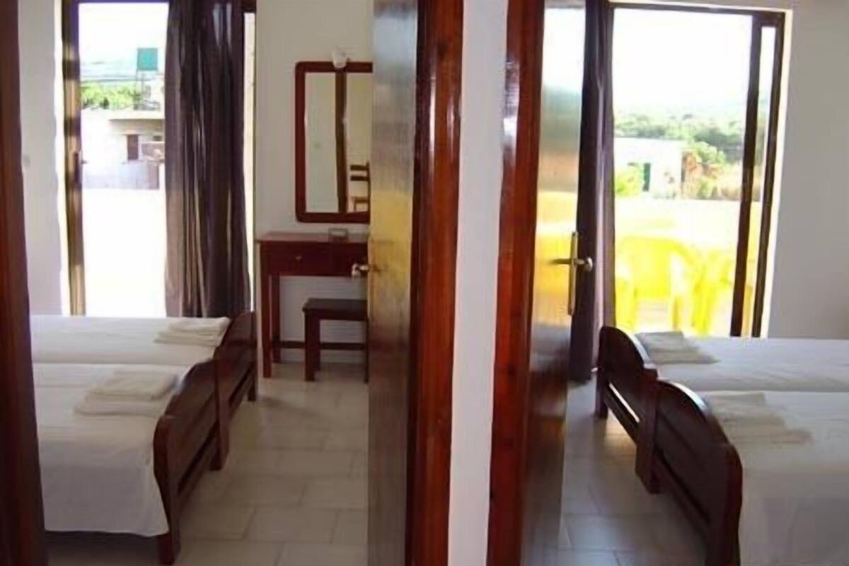 Quarto de hotel com duas camas, uma escrivaninha e uma cadeira.