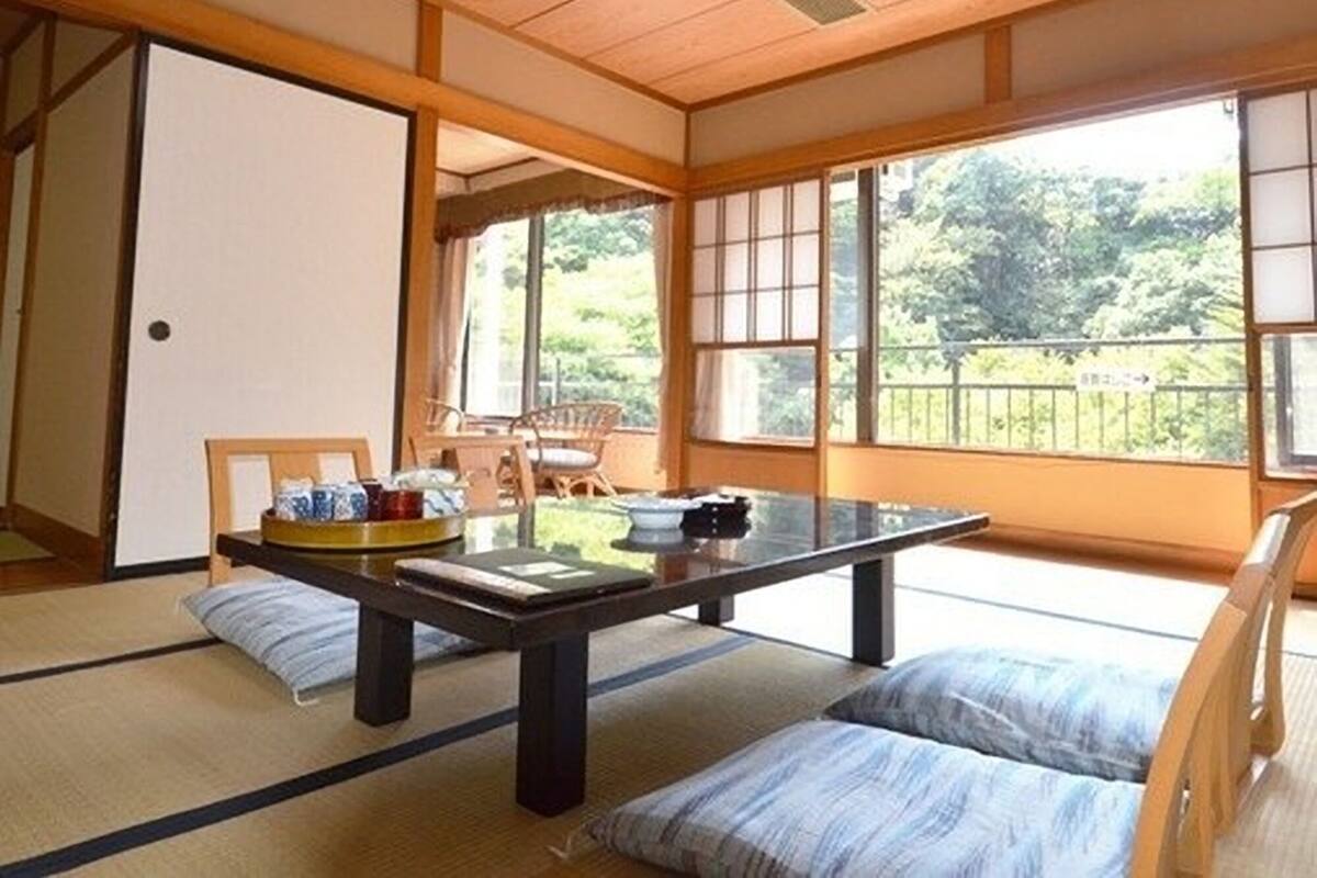 A traditional Japanese room with tatami flooring, a low table, and sliding doors.
