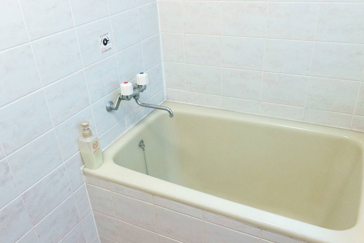 A bathtub with a faucet and a soap dispenser.