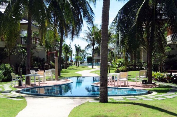 A pool area with palm trees, chairs, and a pathway.