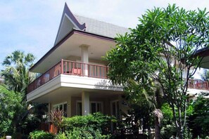 A two-story house with a balcony, surrounded by lush greenery. - Talay Samran by Lease Back Thailand (Cha-am)