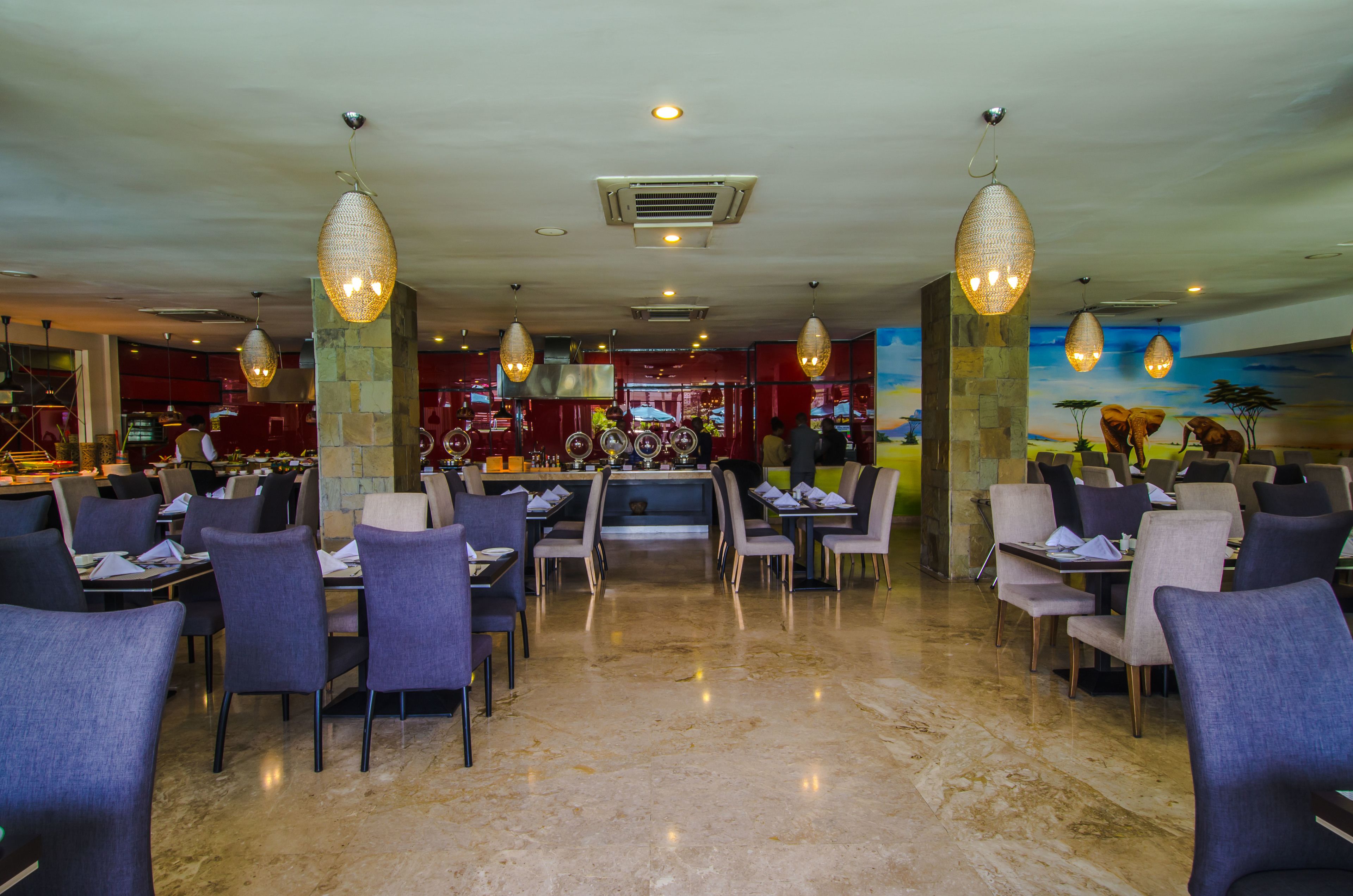 A spacious restaurant with high ceilings, modern pendant lighting, and a central bar area.