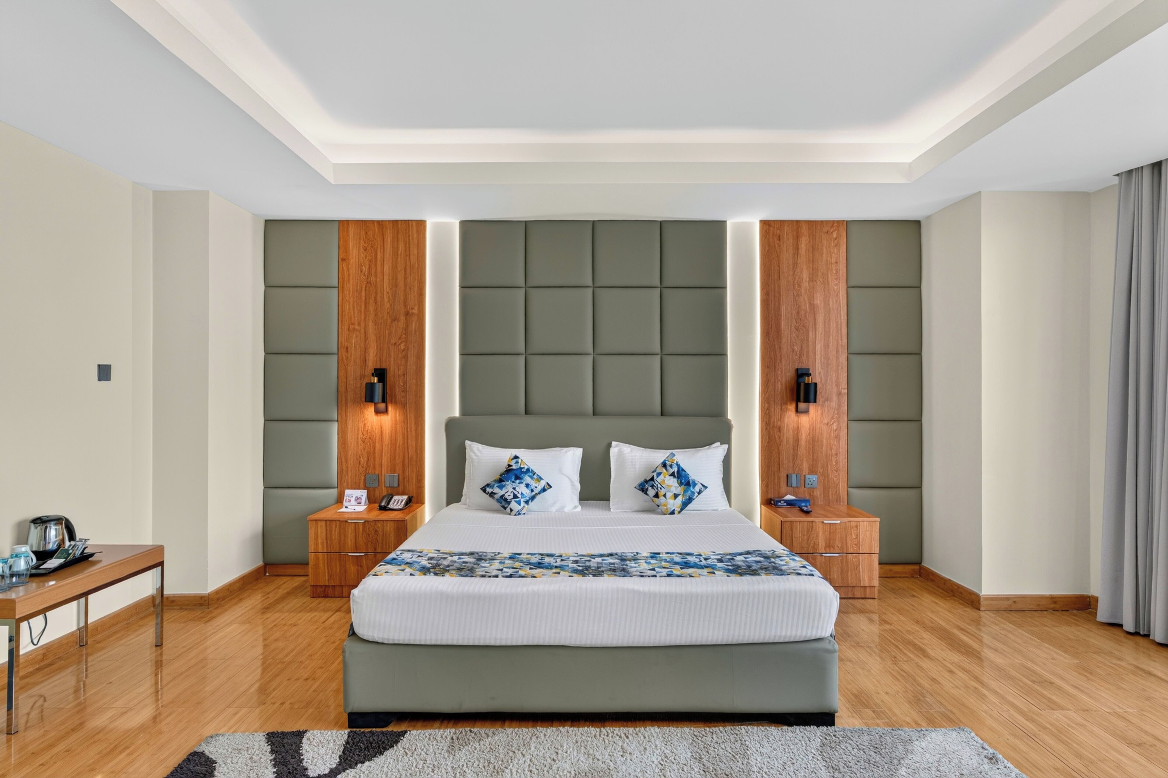 A modern hotel room with a large bed, wooden headboard, and bedside tables with lamps.