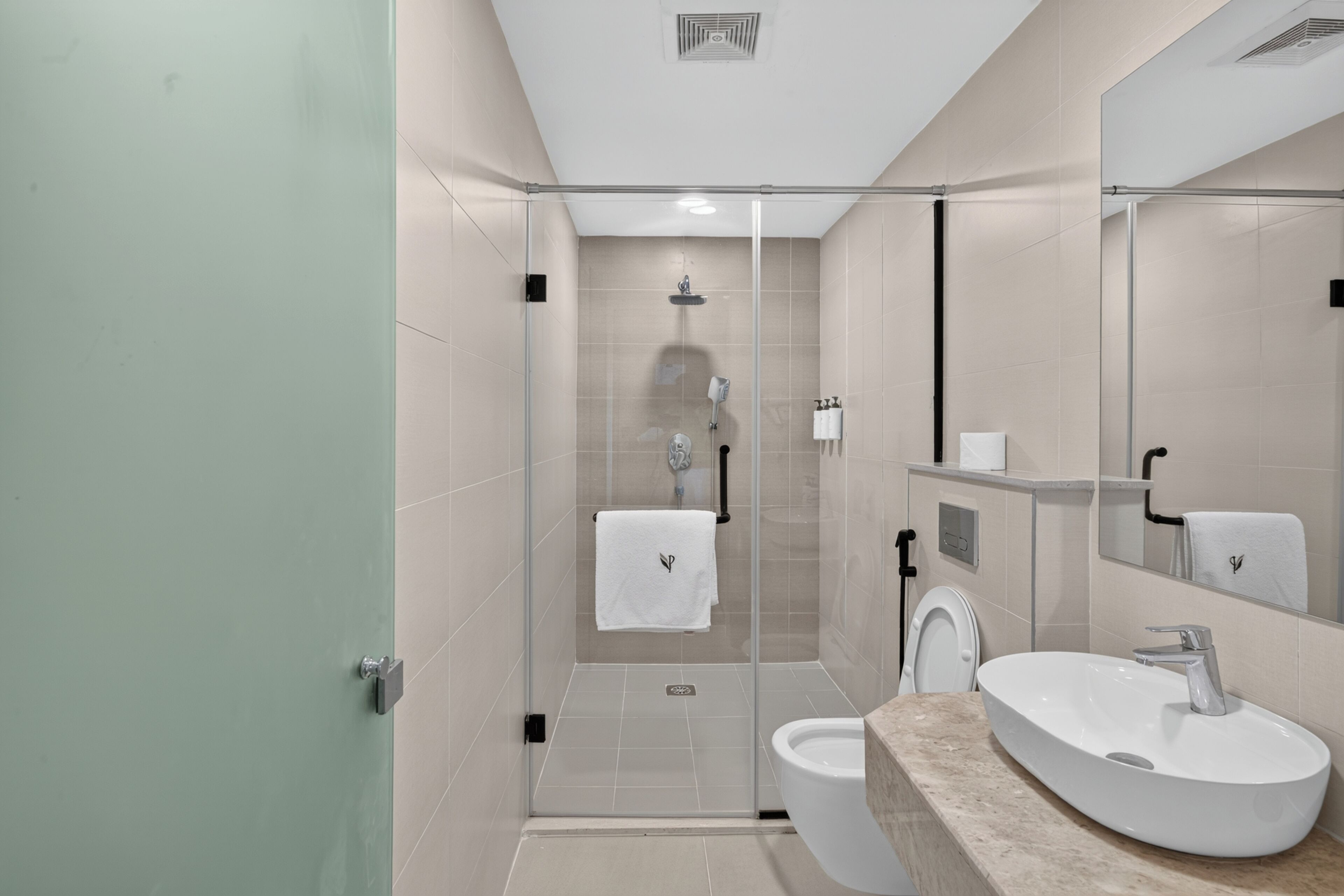 Ein modernes Badezimmer mit einer Duschkabine aus Glas, einem weißen Waschbecken und einer Toilette.