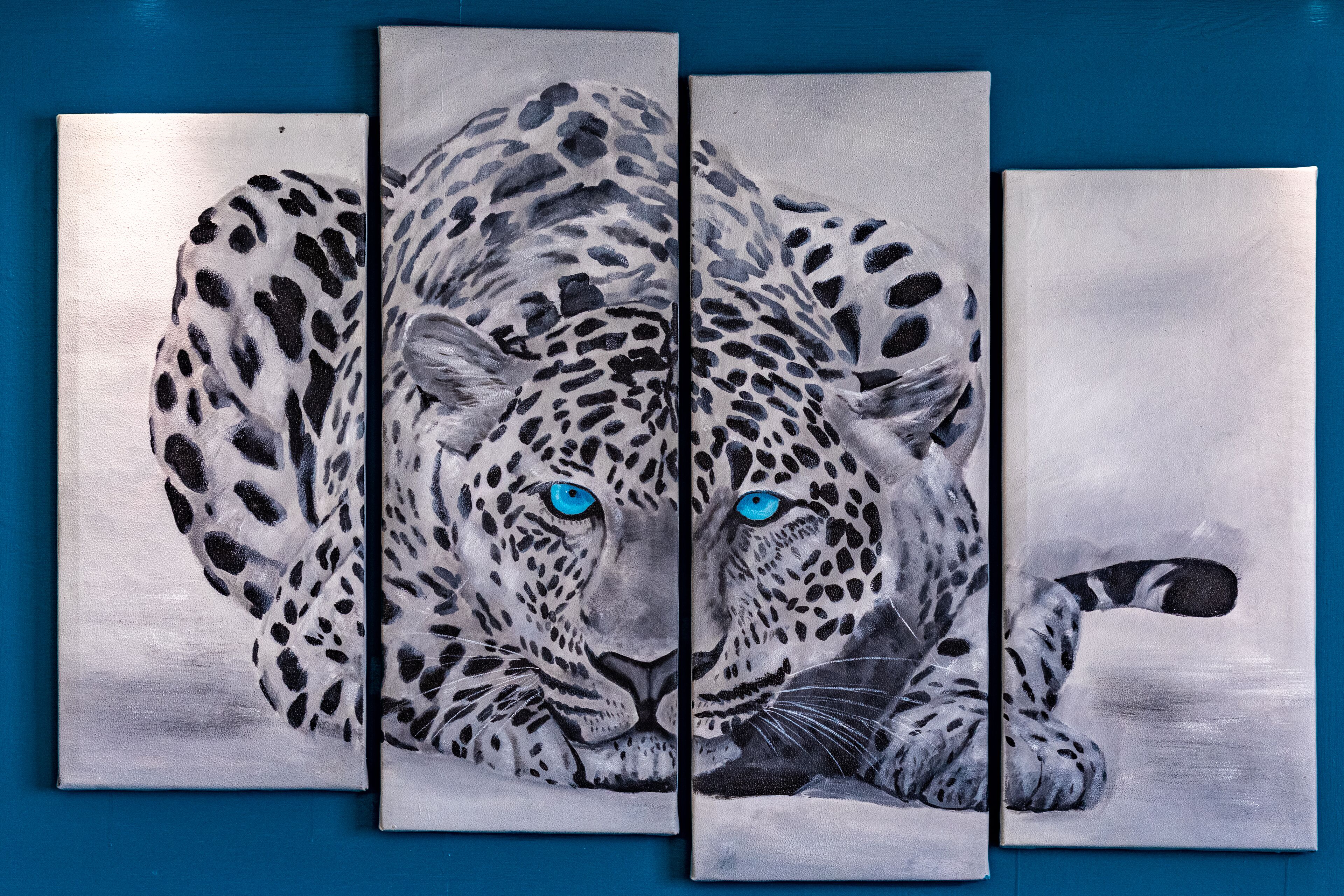 A three-panel painting of a leopard with blue eyes.