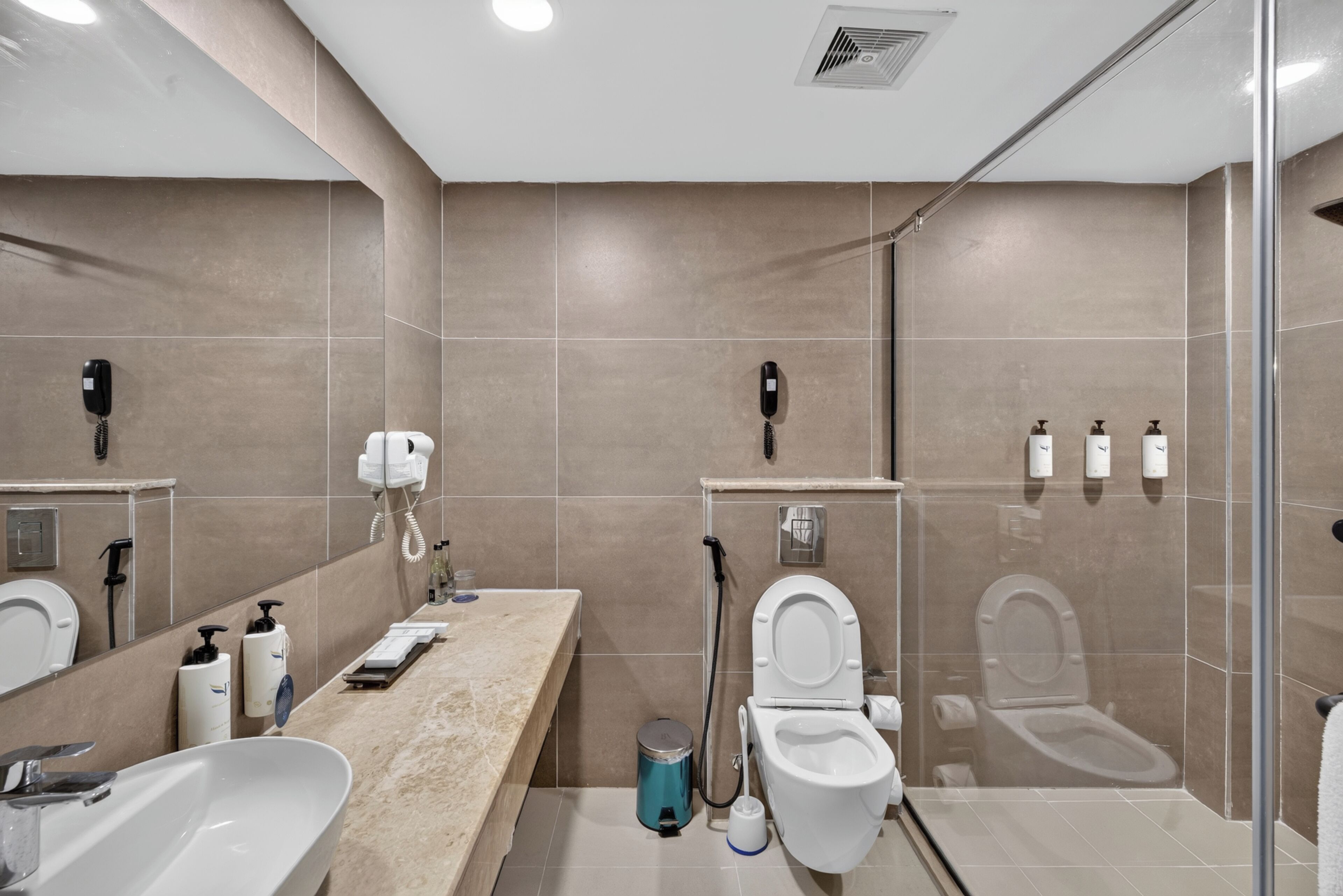 Een moderne badkamer met een grote spiegel, een wastafel, een toilet en een douche.