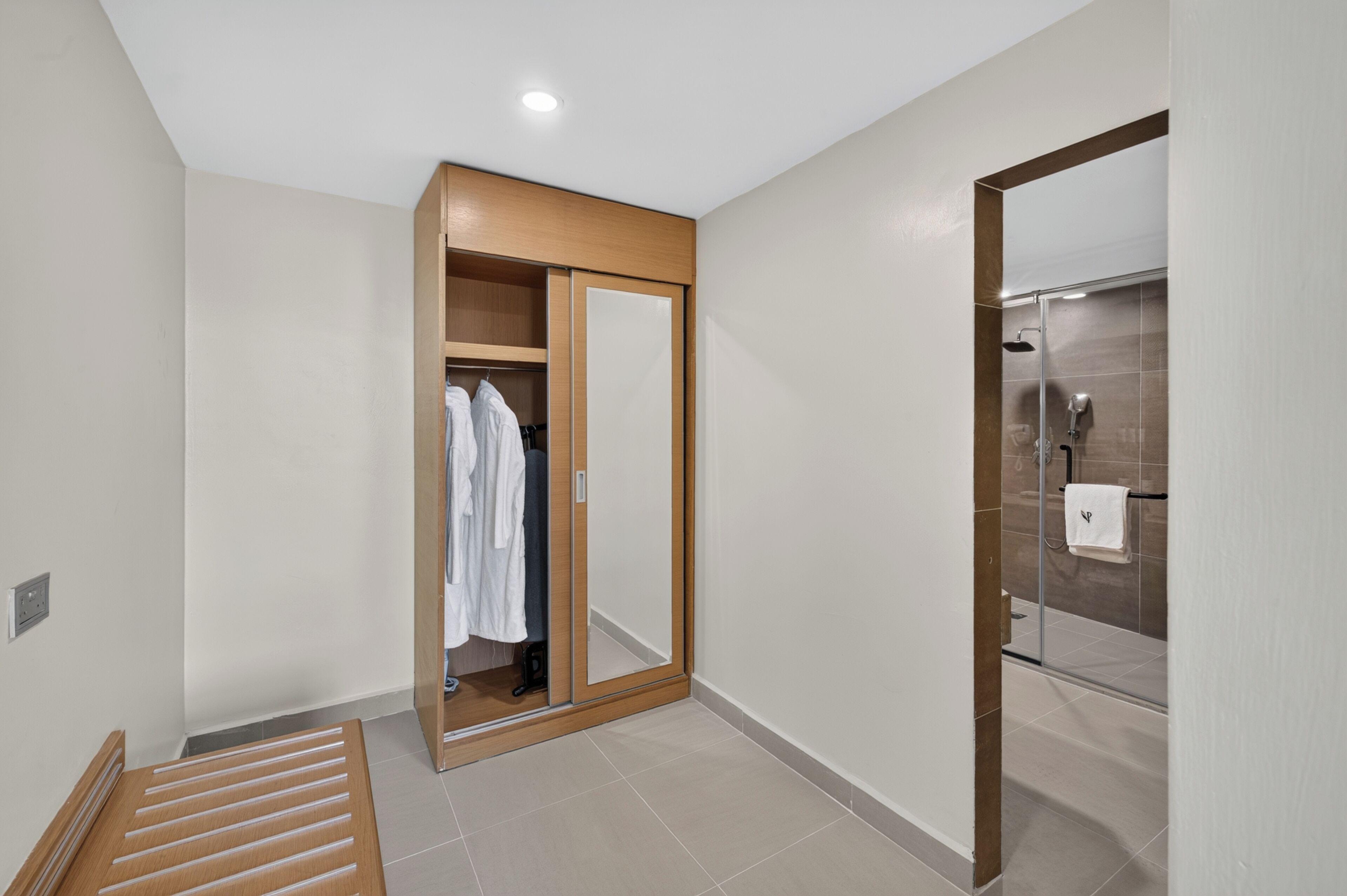 A modern bathroom with a shower, a mirror, and a wooden wardrobe.