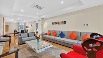 A modern living room with a sofa, coffee table, and a dining area in the background.