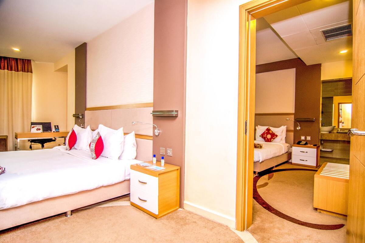 A hotel room with a large bed, bedside tables, a desk, and a mirror.