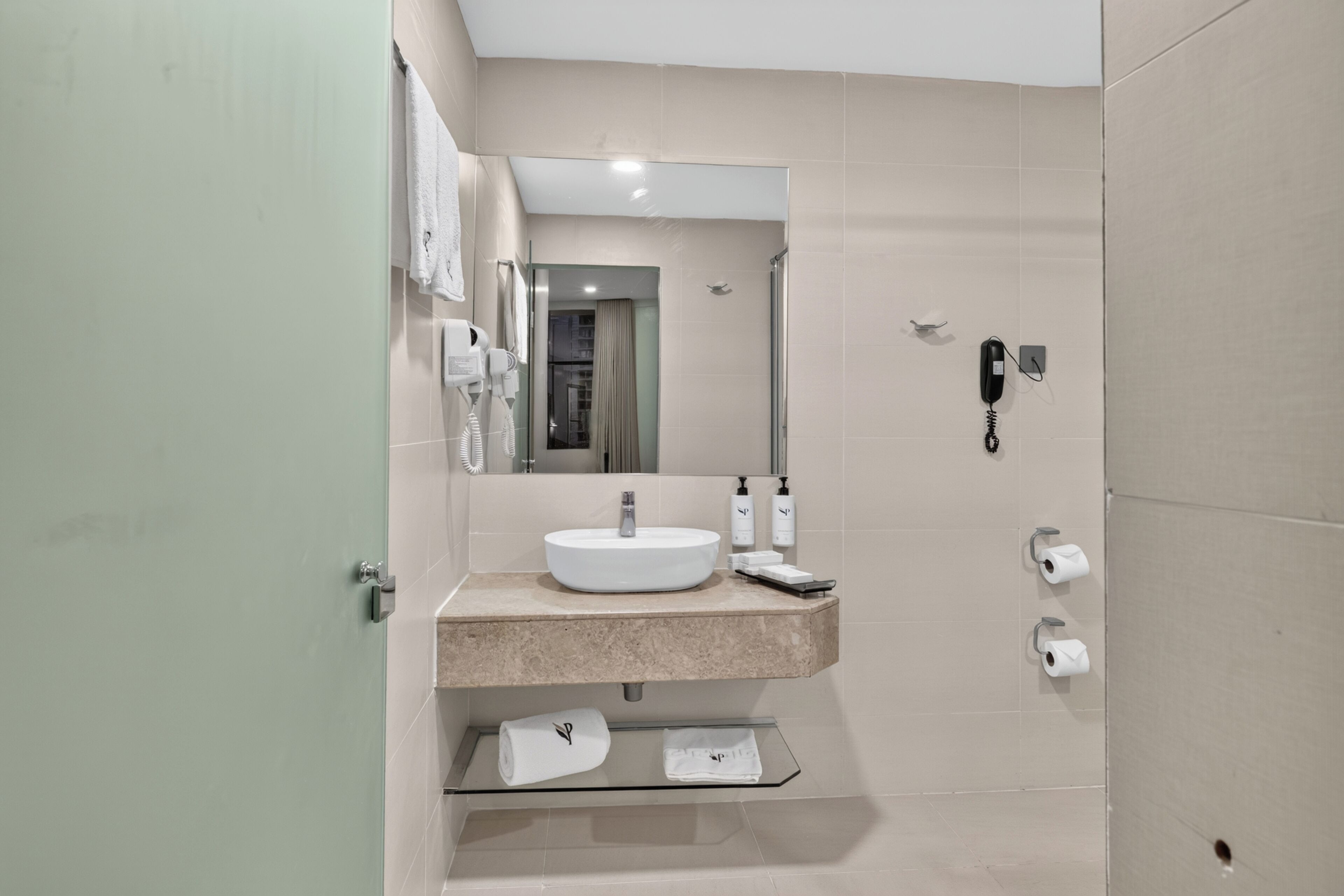 A modern bathroom with a sink, mirror, and toilet paper holder.
