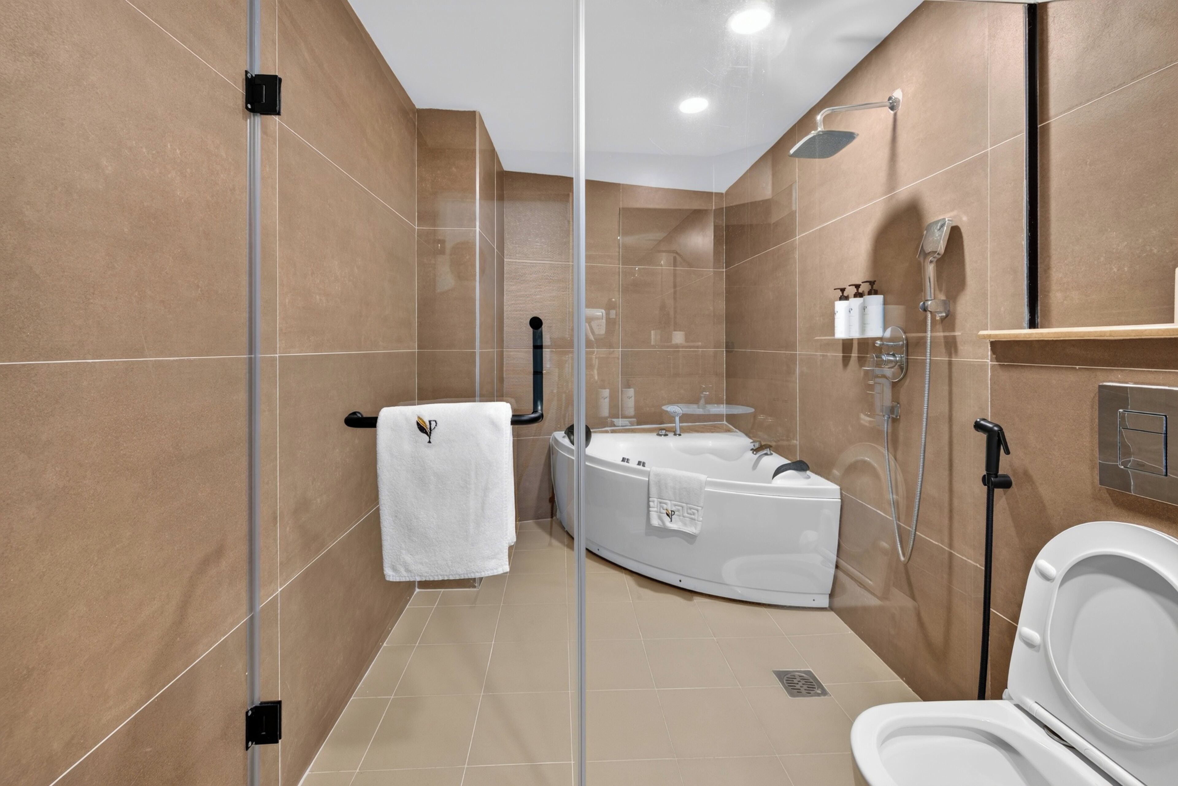 Een moderne badkamer met een glazen douchewand, een badkuip, een douche en een toilet.