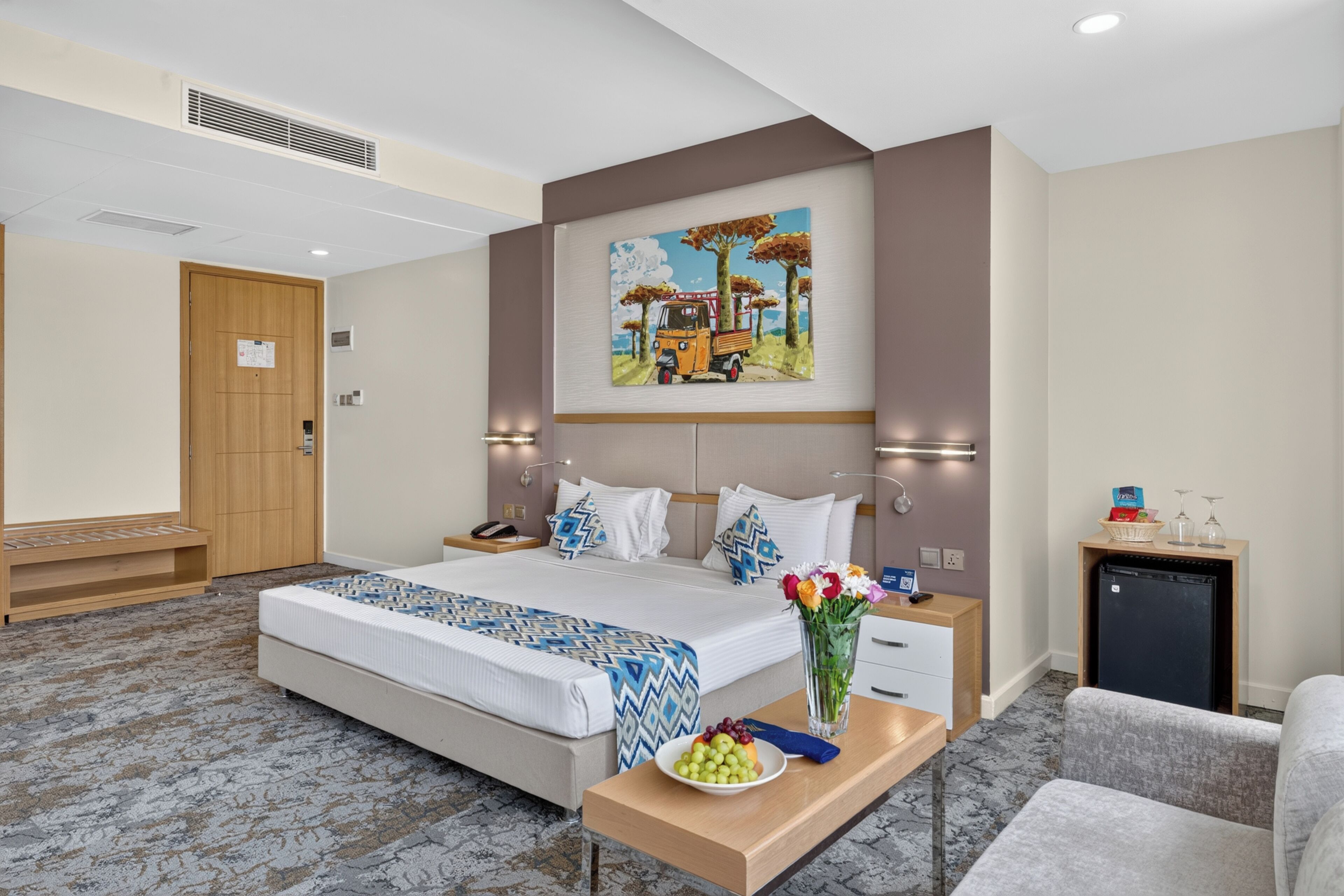 Quarto de hotel com cama, mesa de cabeceira e um quadro na parede.