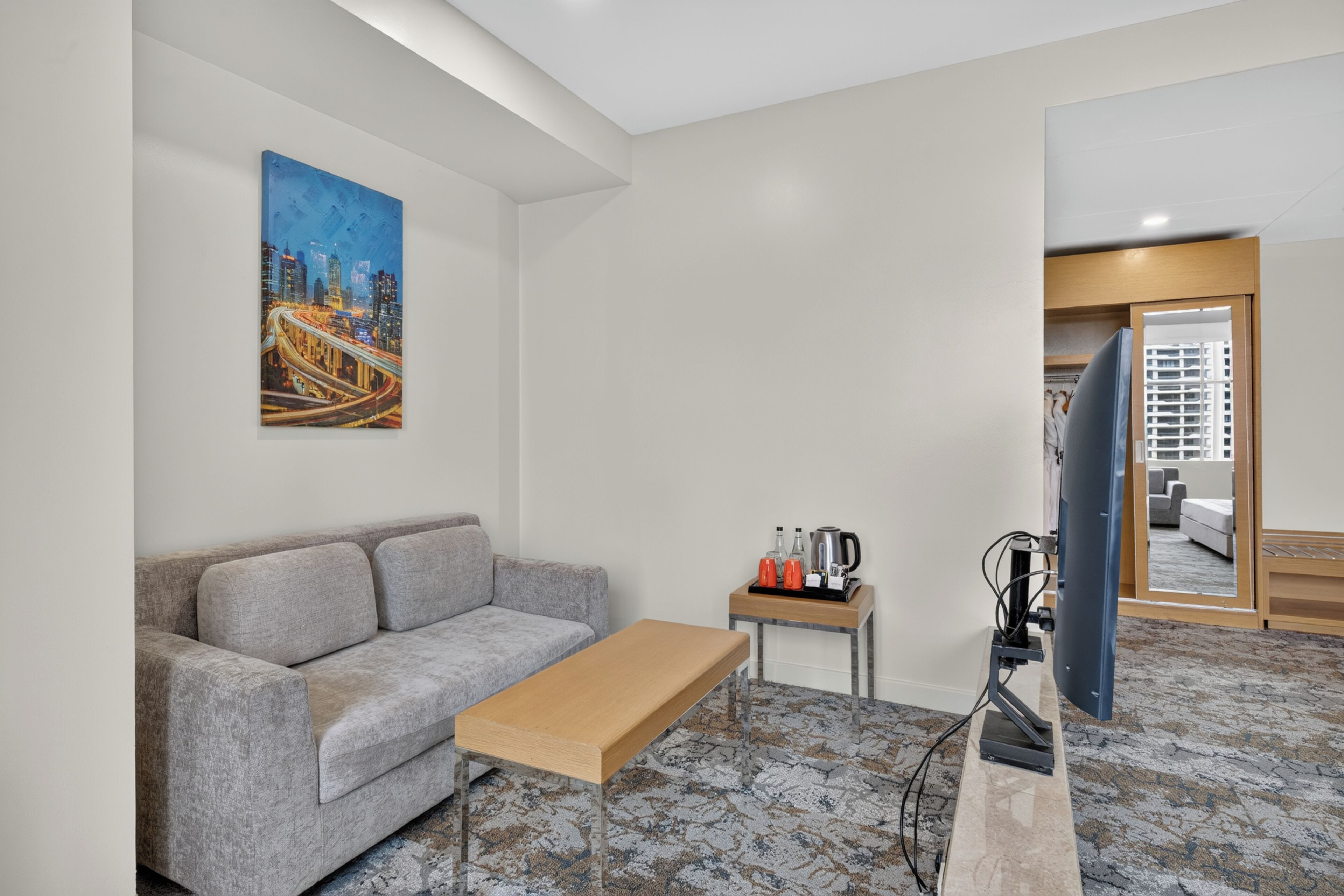 Uma sala de estar moderna com um sofá, uma mesa de centro, uma TV de tela plana e um quadro na parede.