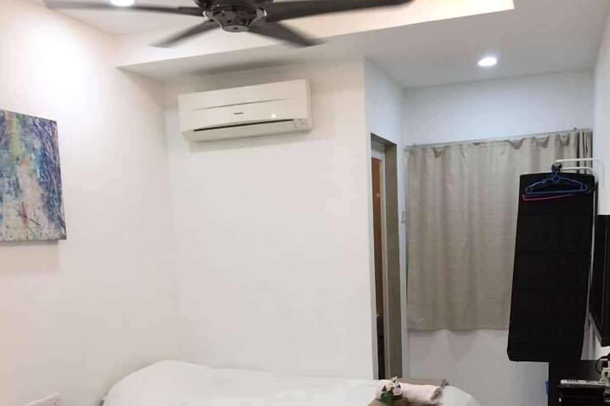 A hotel room with two beds, a ceiling fan, an air conditioning unit, a painting on the wall, and a bathroom with a towel rack and a mirror.