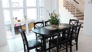 A dining area with a round table, black chairs, and a potted plant. - Nautilus Bay Home Inn (George Town)