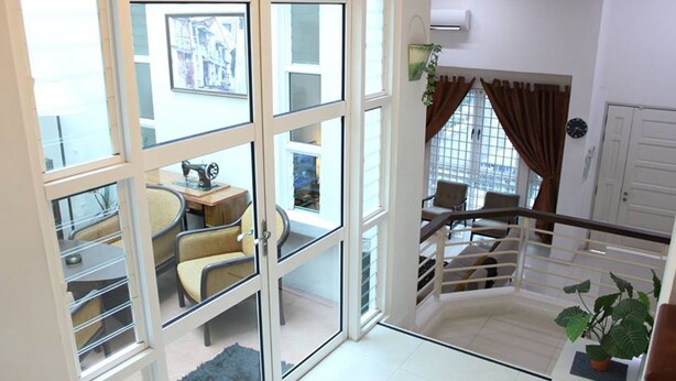 A spacious living area with a large sliding glass door leading to a balcony, a dining area with a table and chairs, and a staircase with a railing. - Nautilus Bay Home Inn (George Town)