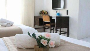 A hotel room with two beds, a desk, a chair, a television, and a small plant. - Nautilus Bay Home Inn (George Town)
