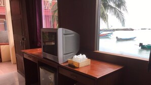 A compact kitchenette with a refrigerator, a microwave, and a small sink. A television is placed on a wooden counter next to a window with a view of boats on water. - Rin Bay View Resort (Ko Pha-ngan)