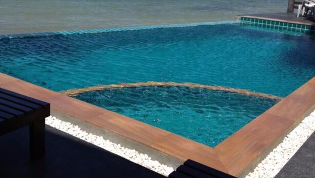 A pool with a wooden deck and white pebbles, overlooking the ocean. - Rin Bay View Resort (Ko Pha-ngan)