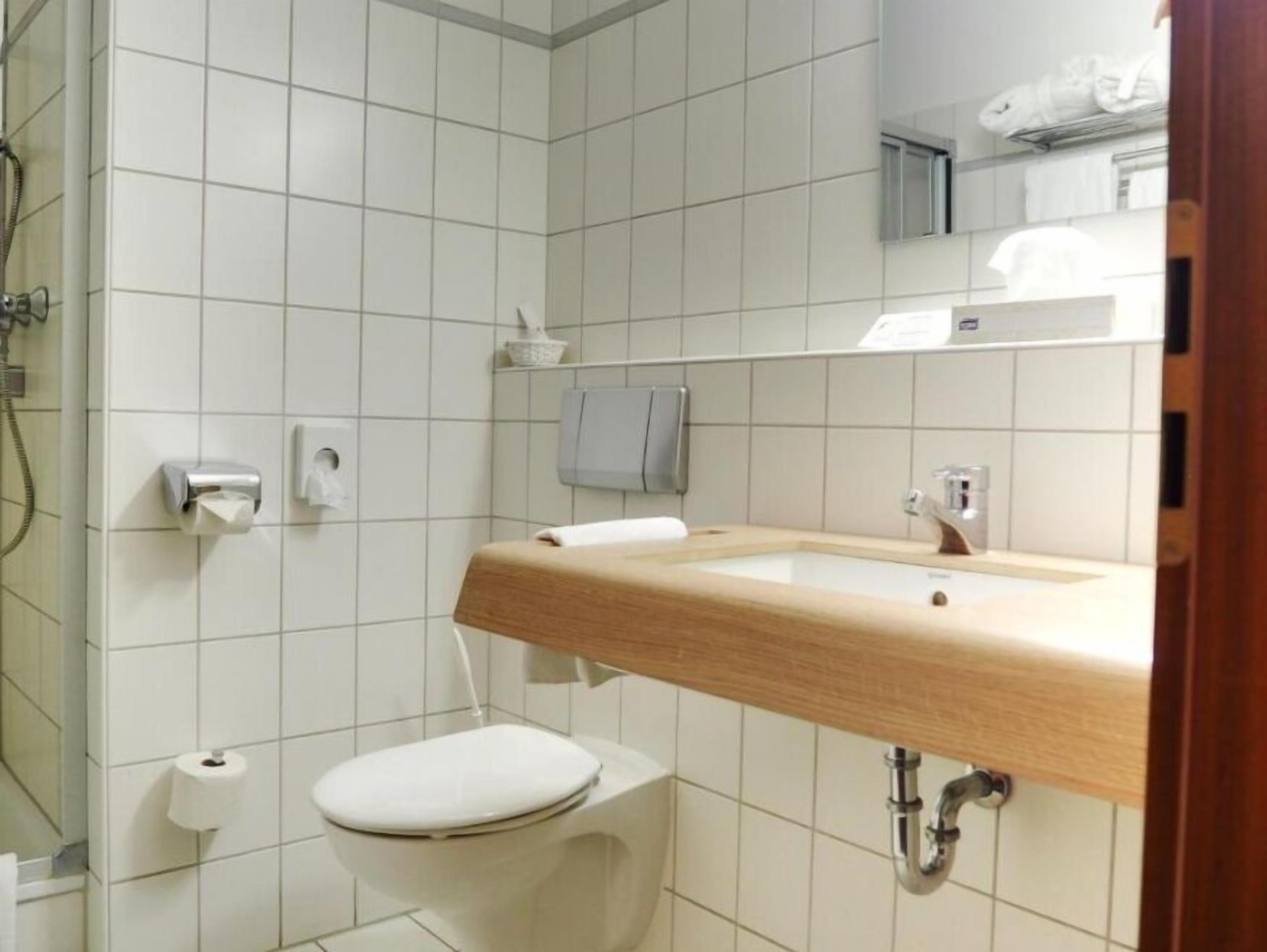 A bathroom with a toilet, sink, and shower.