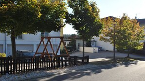 A residential street with houses, a swing set, and a paved road. - Heidehotel Lubast (Kemberg)