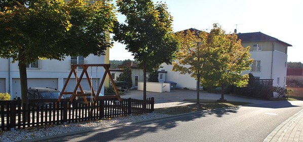 A residential street with houses, a swing set, and a paved road.