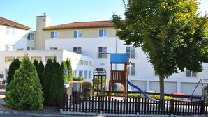 A residential building with a playground, a fence, and a tree. - Heidehotel Lubast (Kemberg)