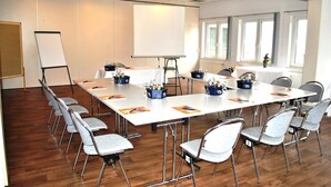 A conference room with a long table, chairs, a whiteboard, and a projector screen. - Heidehotel Lubast (Kemberg)