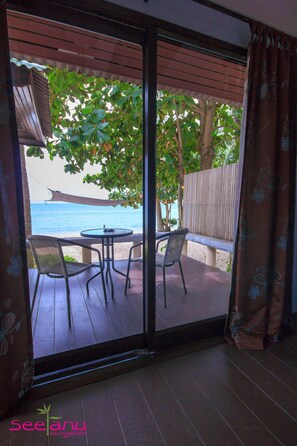 A room with a sliding glass door leading to a balcony with a view of the sea. There is a table and two chairs on the balcony. - Seetanu Bungalows (Ko Pha-ngan)