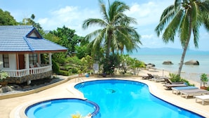 Piscina com espreguiçadeiras e vista para o oceano.