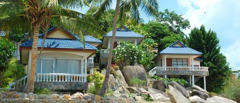 A beachfront property with multiple houses, each featuring a balcony and a stone wall.