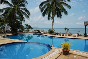 A swimming pool with lounge chairs and palm trees, overlooking a body of water. - Phangan Orchid Resort (Ko Pha-ngan)