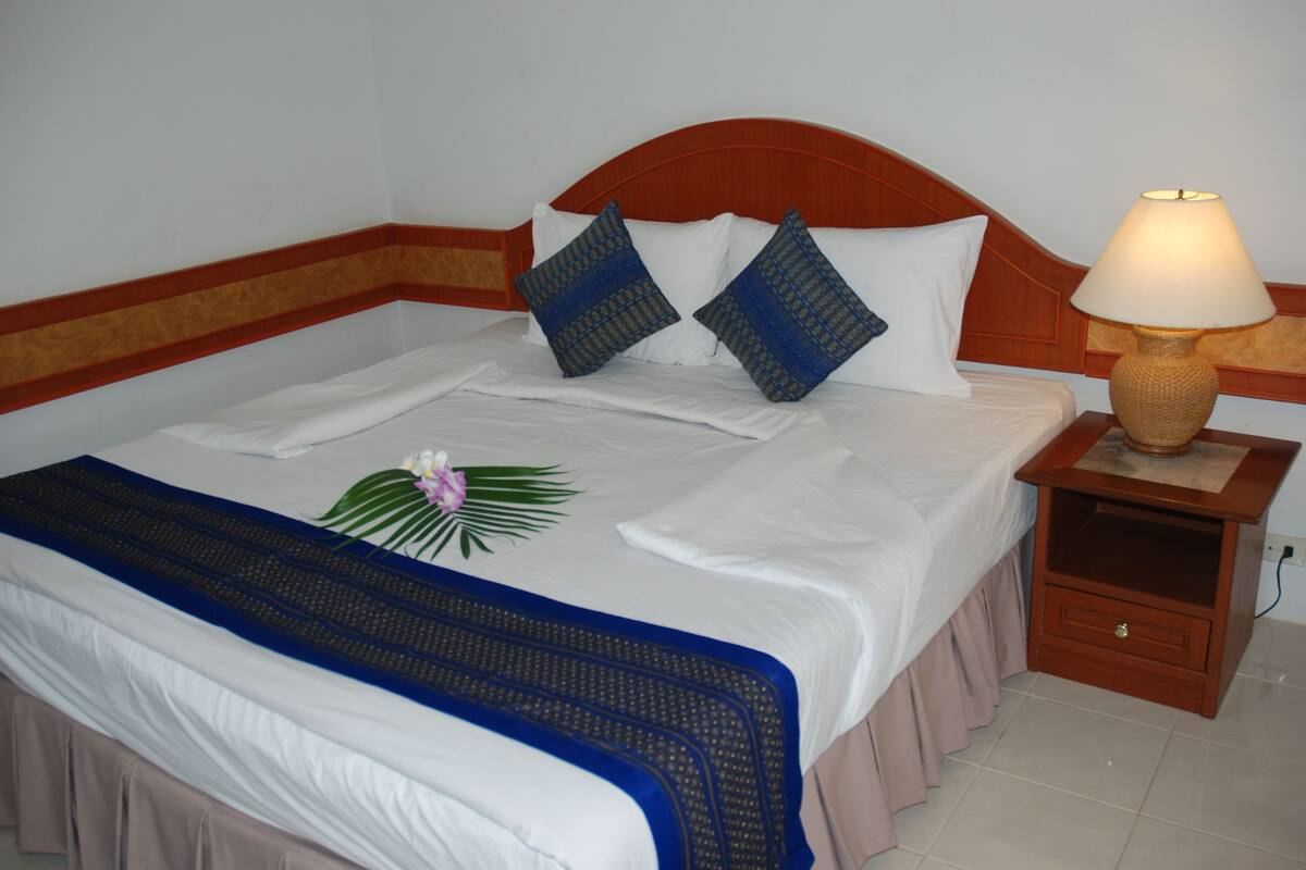 A neatly made bed with white bedding, two blue patterned pillows, and a decorative flower arrangement.