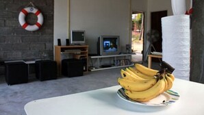 A room with a white table, a wall-mounted life preserver, a television, and a stack of white paper towels. - Monkey Samui Hostel (Koh Samui)