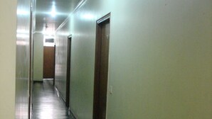 A hallway with a checkered floor, doors on one side, and a light at the end. - Westend Holiday Home (New Delhi)
