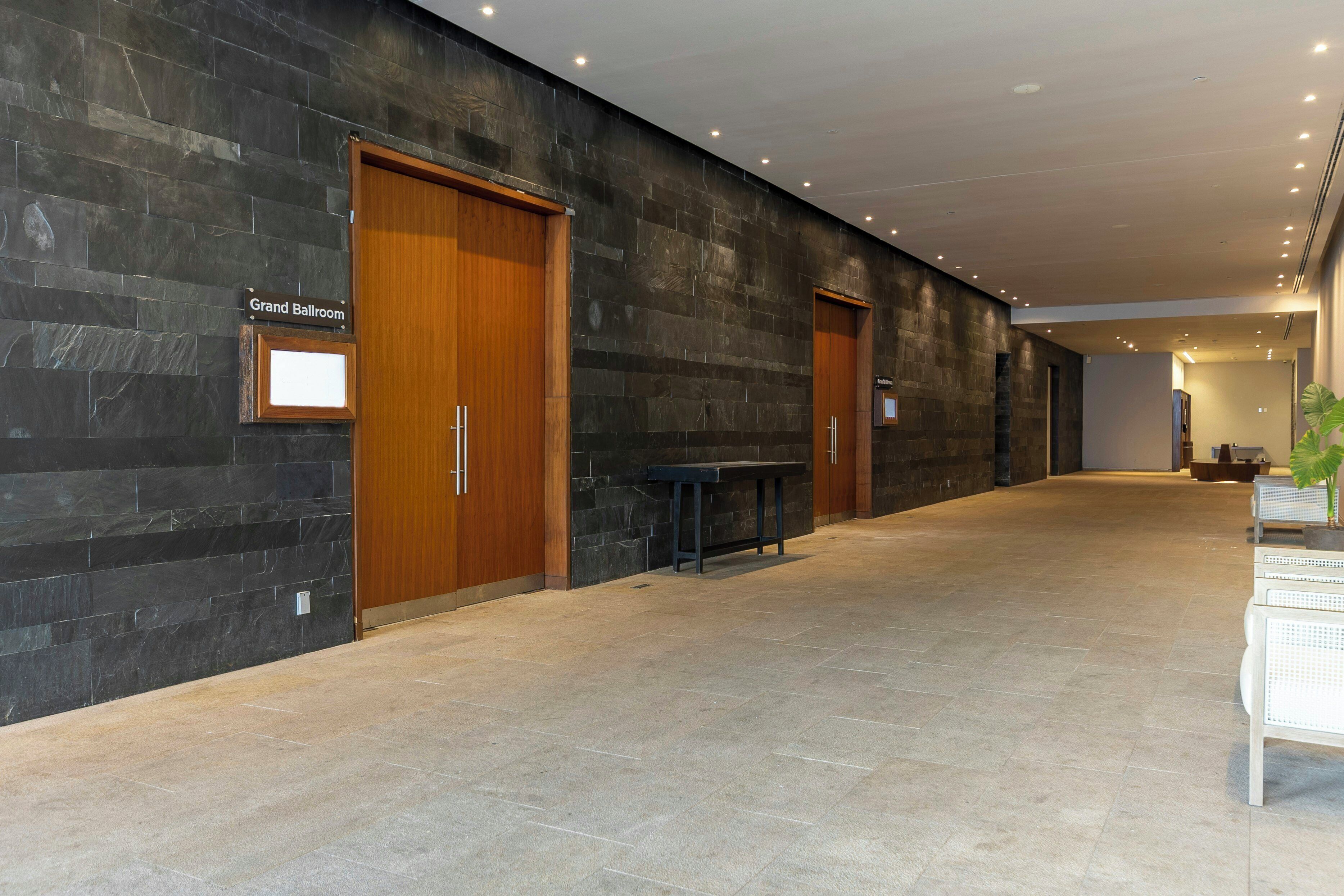 A hallway with dark stone walls, wooden doors, and a bench.