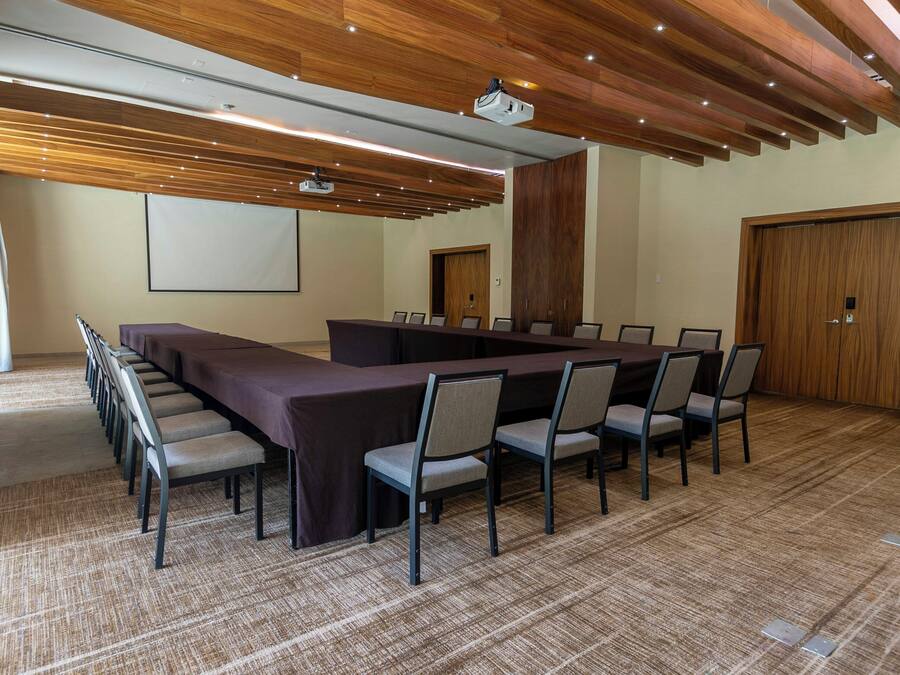 A conference room with a long table, chairs, a projector, and a screen.