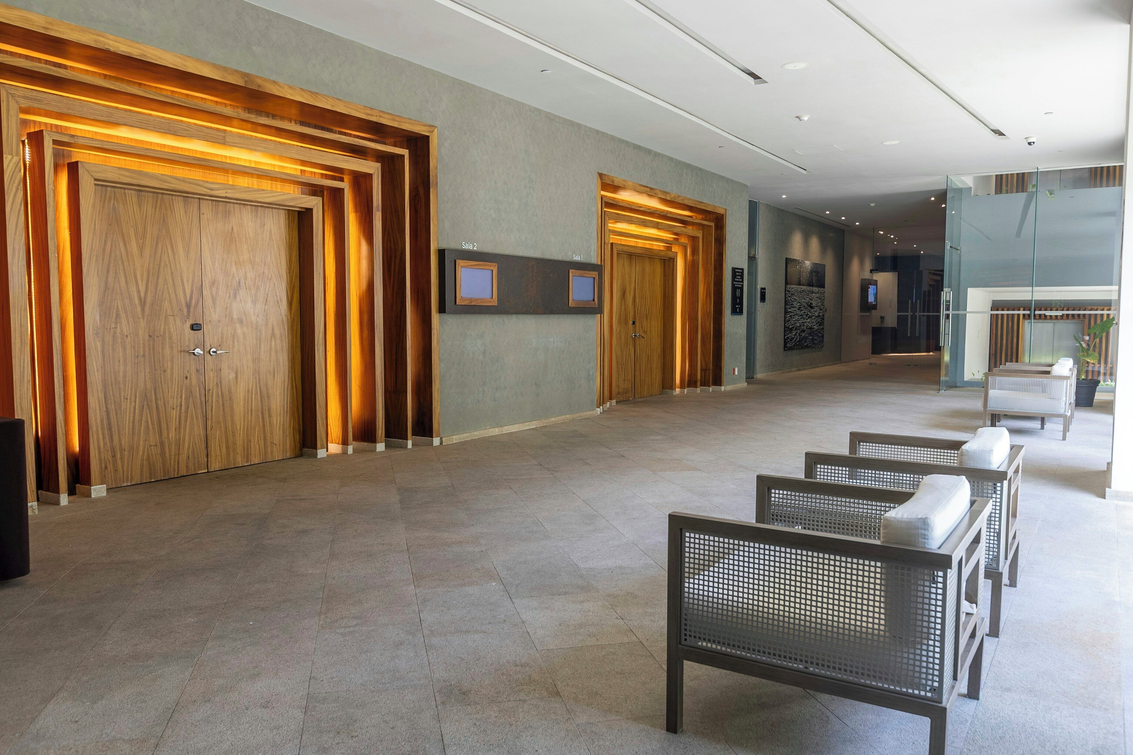 Een hotel lobby met houten deuren, een receptiebalie en zitgedeeltes.