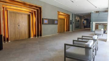 Een hotel lobby met houten deuren, een receptiebalie en zitgedeeltes.