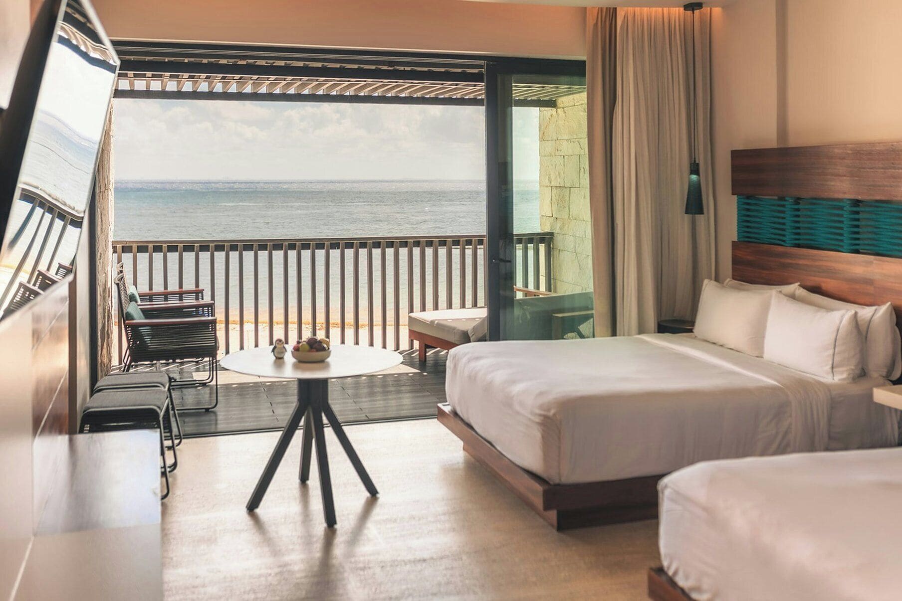 Una habitación de hotel con cama, una mesita, una silla y vista al mar.