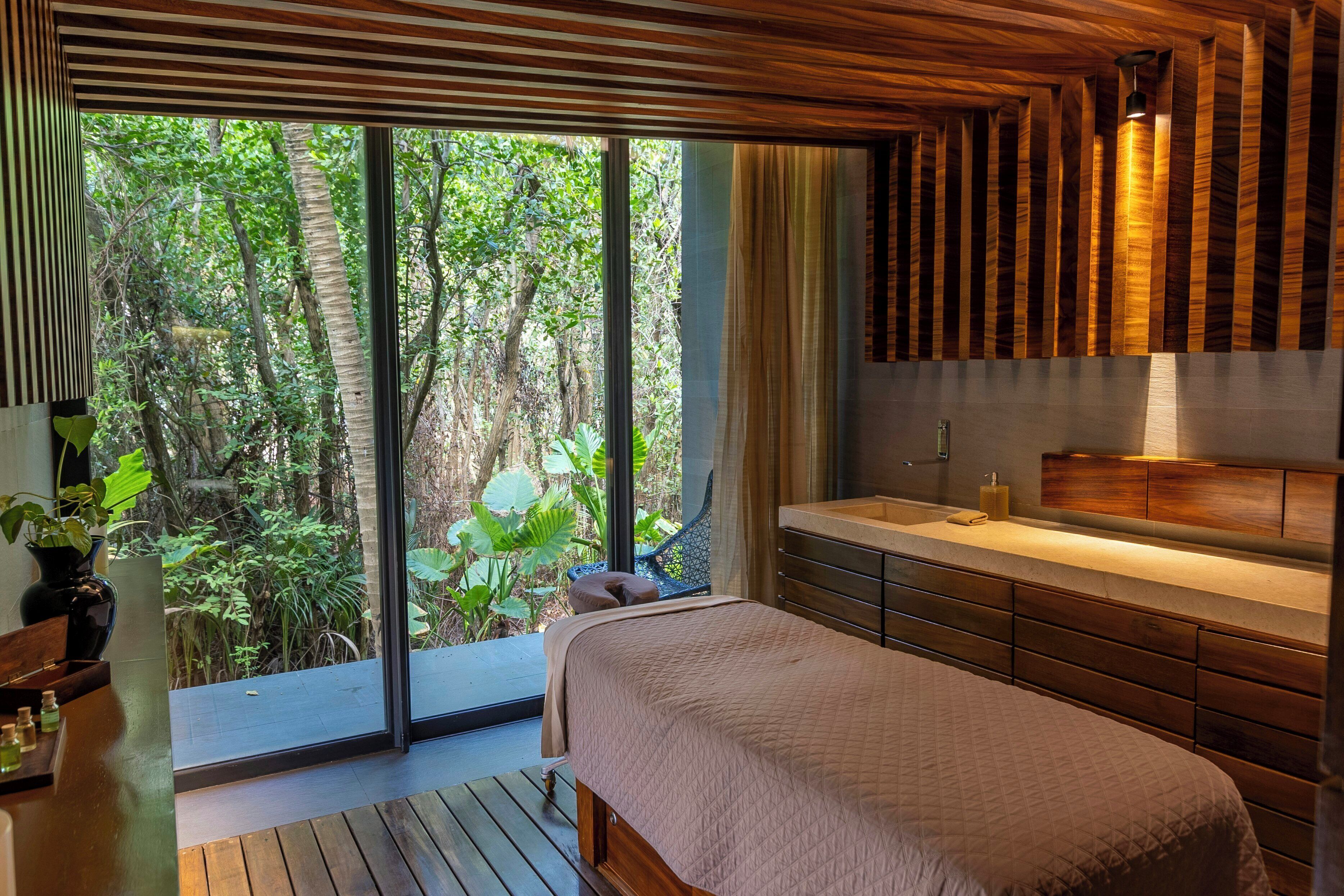 A bedroom with a large window, wooden ceiling, and a bed with a headboard.
