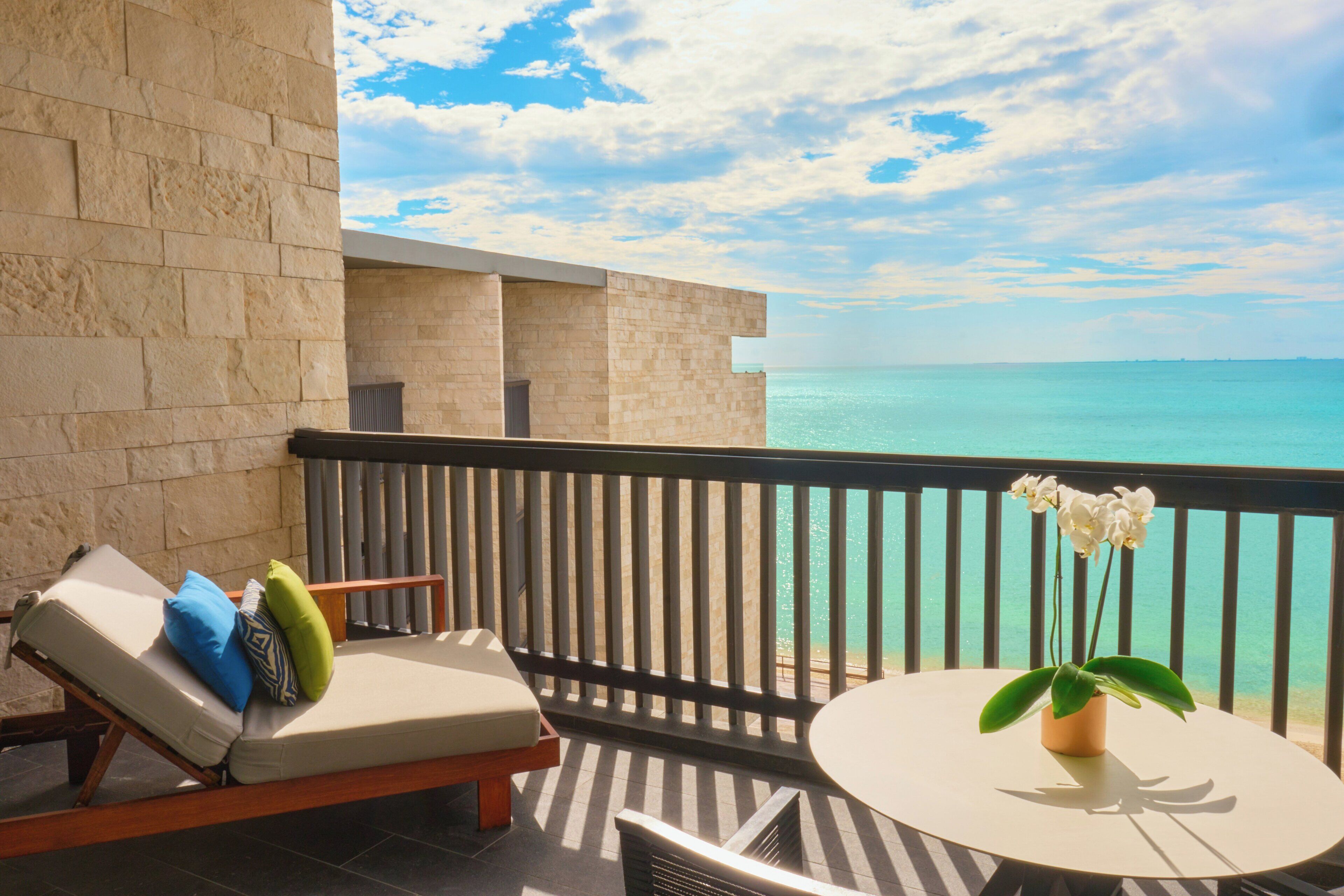 A balcony with a lounge chair, a small table, and a potted orchid.
