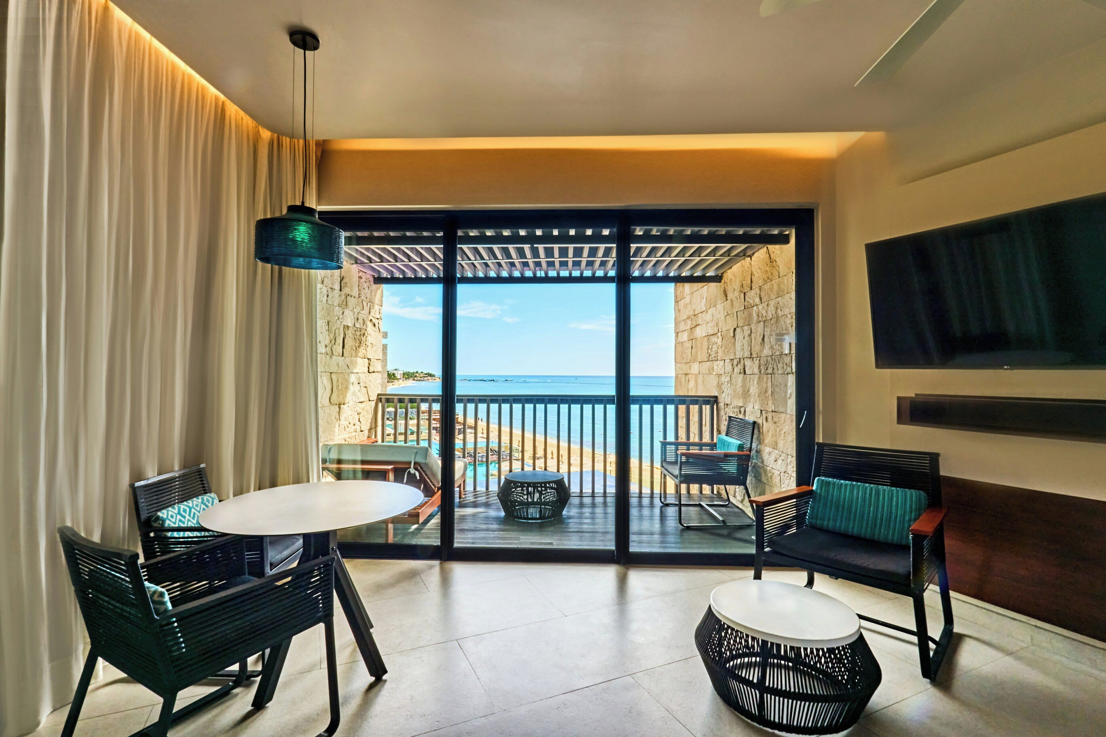 A balcony with a view of the beach, furnished with a table and chairs.
