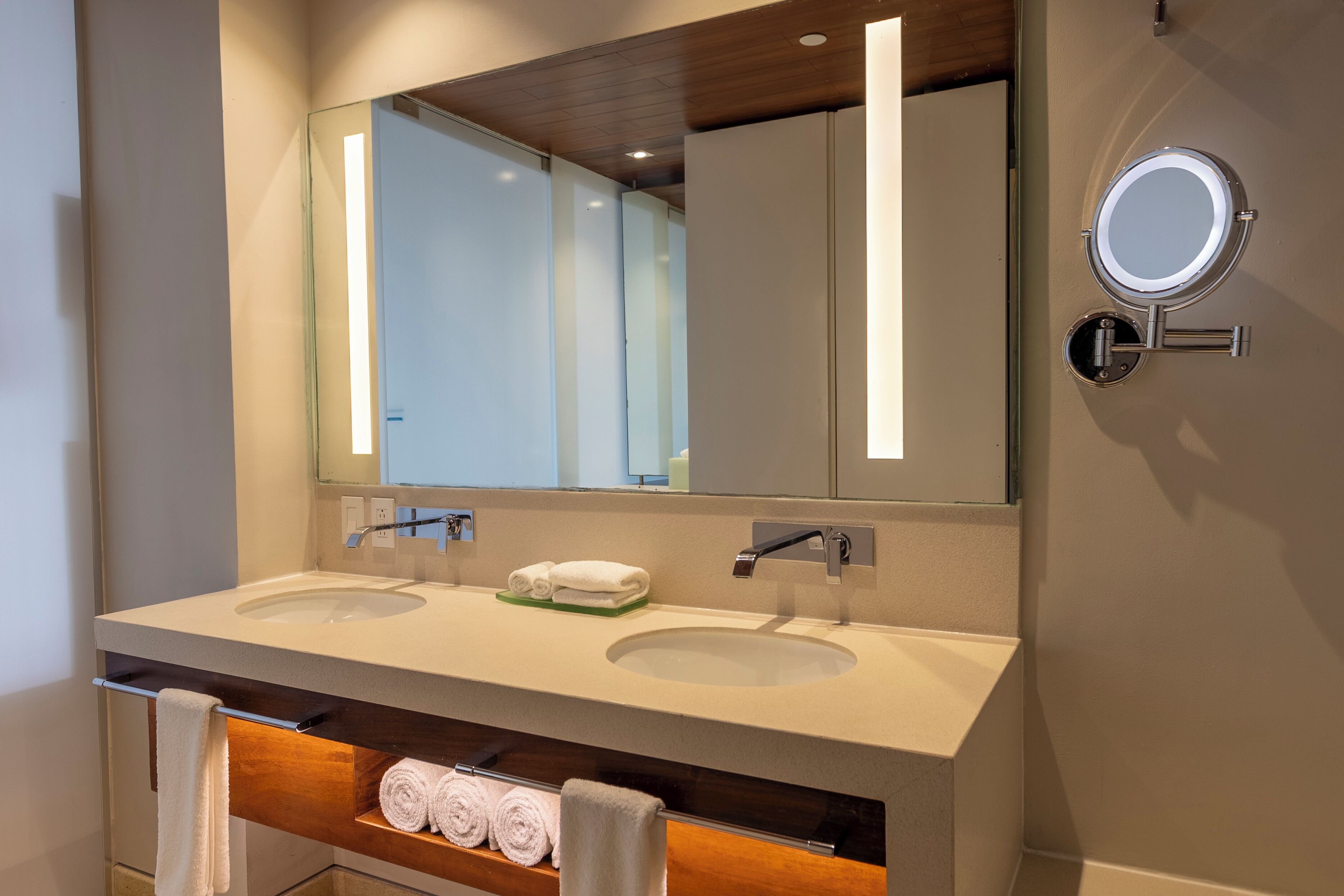 A modern bathroom with two sinks, a large mirror, and a towel rack.