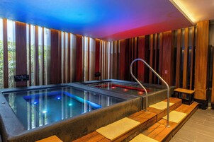 Un espacio de spa con una bañera de hidromasaje, paredes de paneles de madera y una escalera metálica.