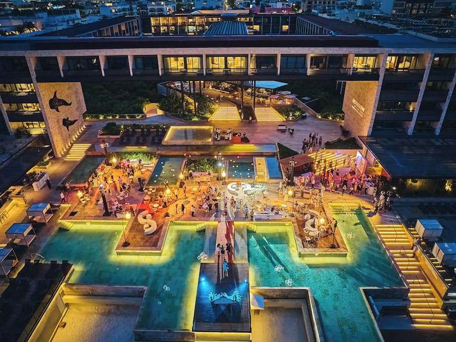 Vista aérea de um hotel com área de piscina, espaço para sentar ao ar livre e palco para eventos.