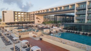 A rooftop pool area with multiple lounge chairs and umbrellas, a large pool, and a building with balconies and a leopard mural.