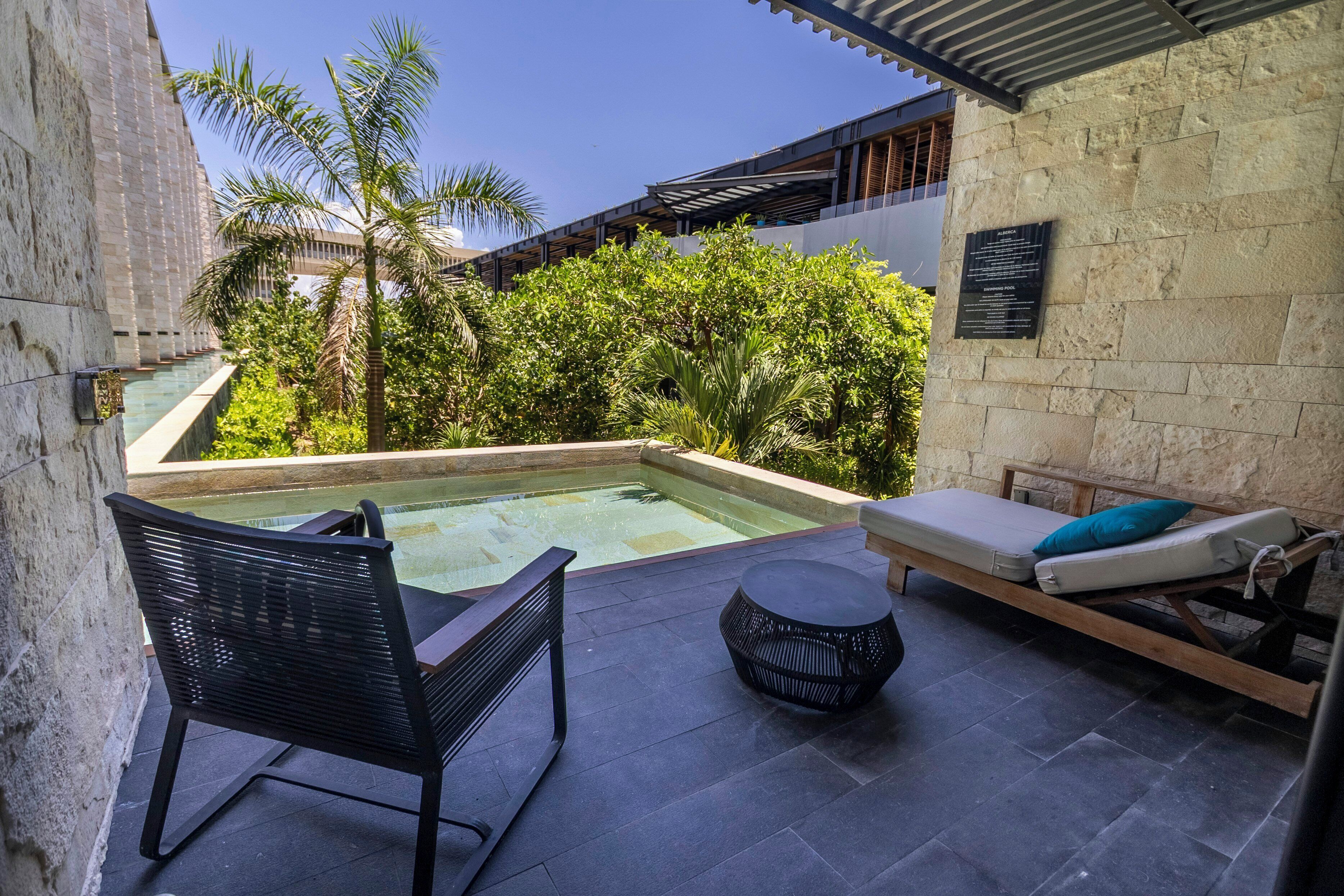 A rooftop pool area with a lounge chair, a small table, and a chair.