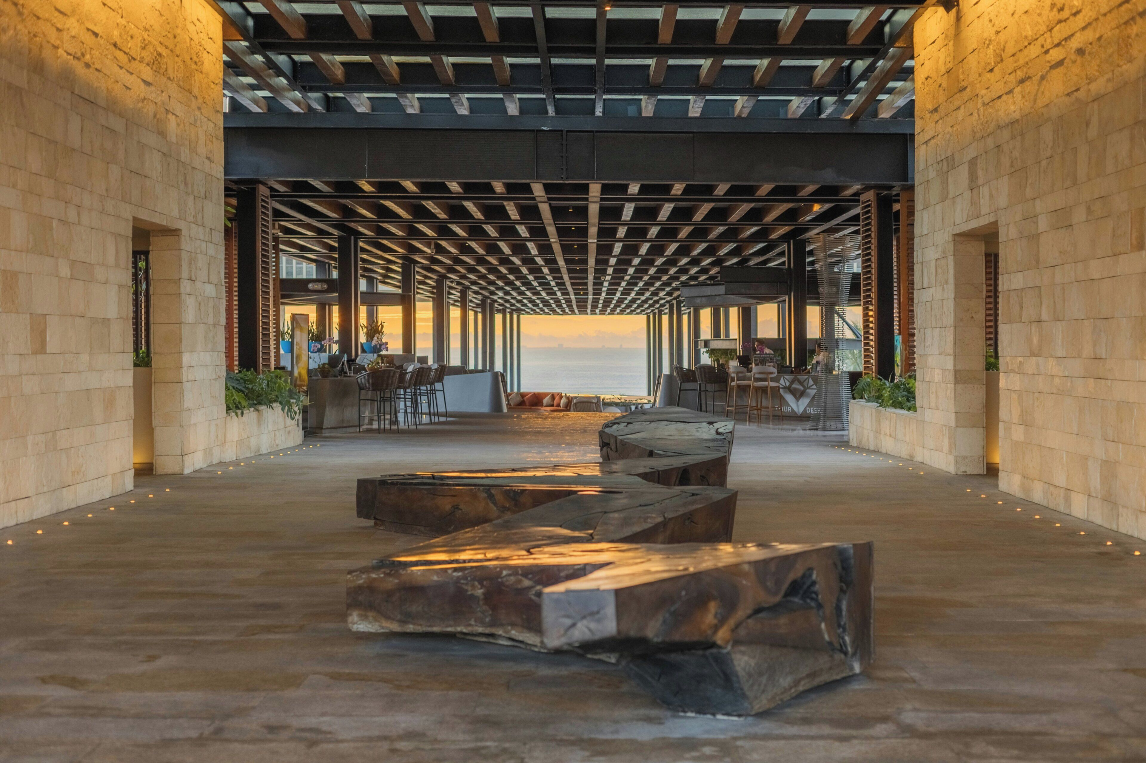 An indoor area with a view of the sea, featuring a wooden bench, seating area, and a bar.