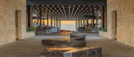 Un espacio interior con vista al mar, que incluye un banco de madera, zona de estar y un bar.